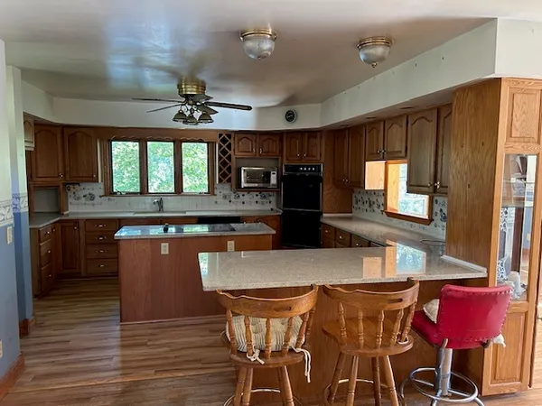 a kitchen with stainless steel appliances granite countertop a kitchen island hardwood floor sink stove dining table and chairs