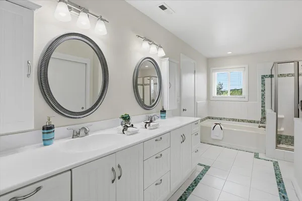 a spacious bathroom with a double vanity sink mirror and a bathtub