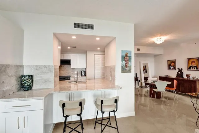 a kitchen with stainless steel appliances kitchen island granite countertop a table and chairs in it