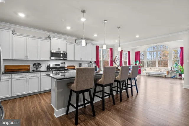 a kitchen with kitchen island granite countertop a dining table chairs and white cabinets