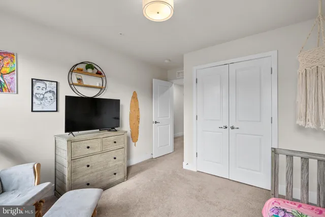 a bedroom with a bed television on desk and a window
