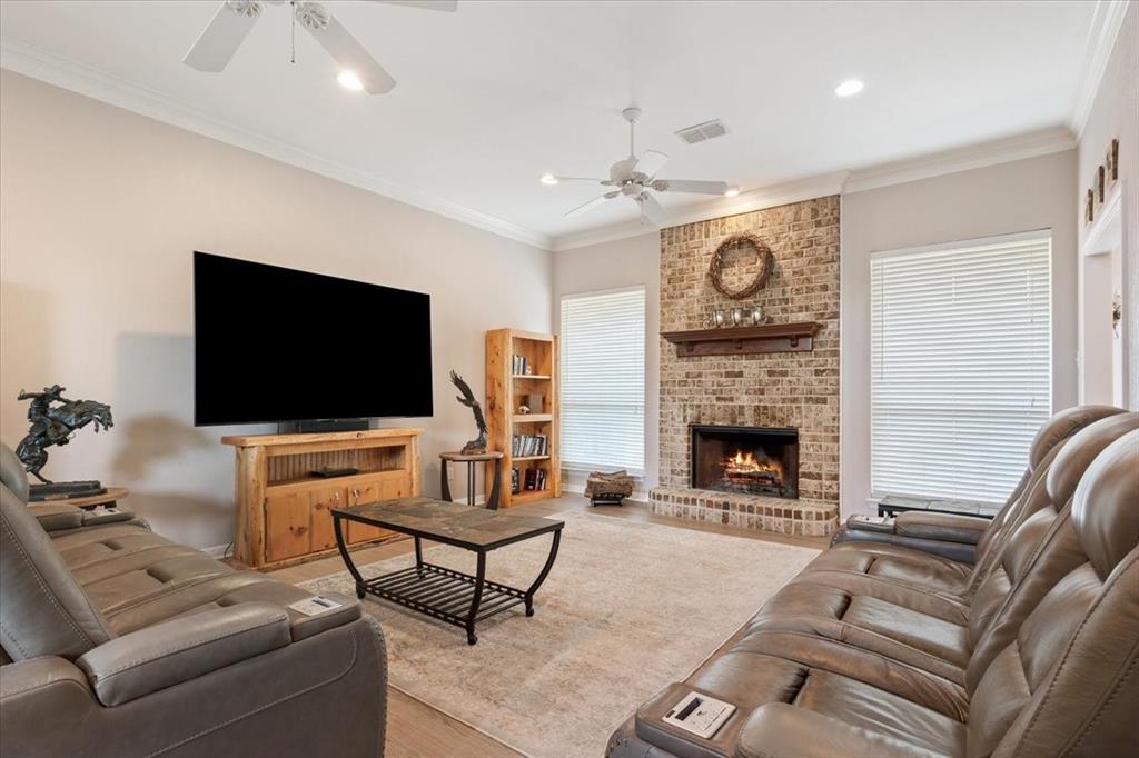 111 Spring Creek Street Waco, TX 76705 - Photo 10 of 40 Brick fireplace with a wood mantle, crown molding, ceiling fans, and wood-finish flooring