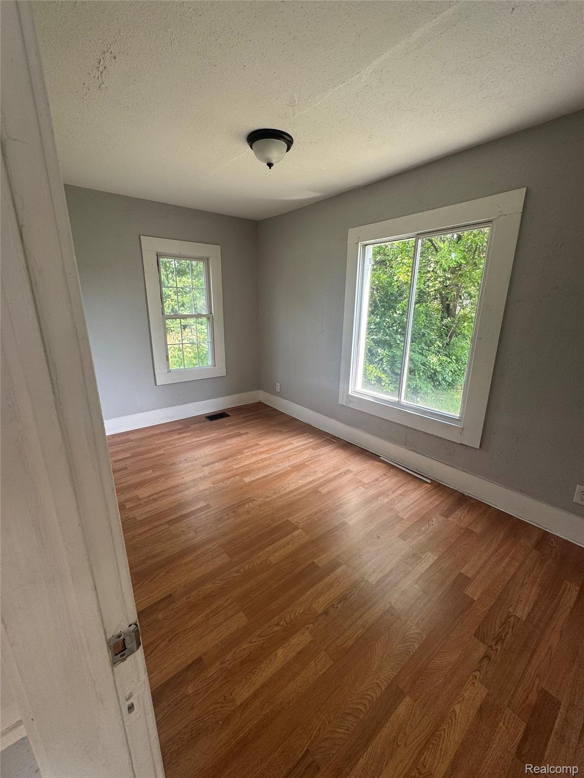 2176 Springle Street Detroit, MI 48215 - Photo 6 of 9 Room featuring wood-finish flooring, light grey painted walls, white trim, and two windows