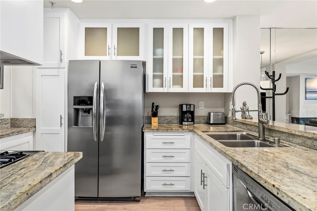2000 Pacific Coast Highway, Unit 102 Huntington Beach, CA 92648 - Photo 11 of 35 a kitchen with granite countertop a refrigerator and a sink