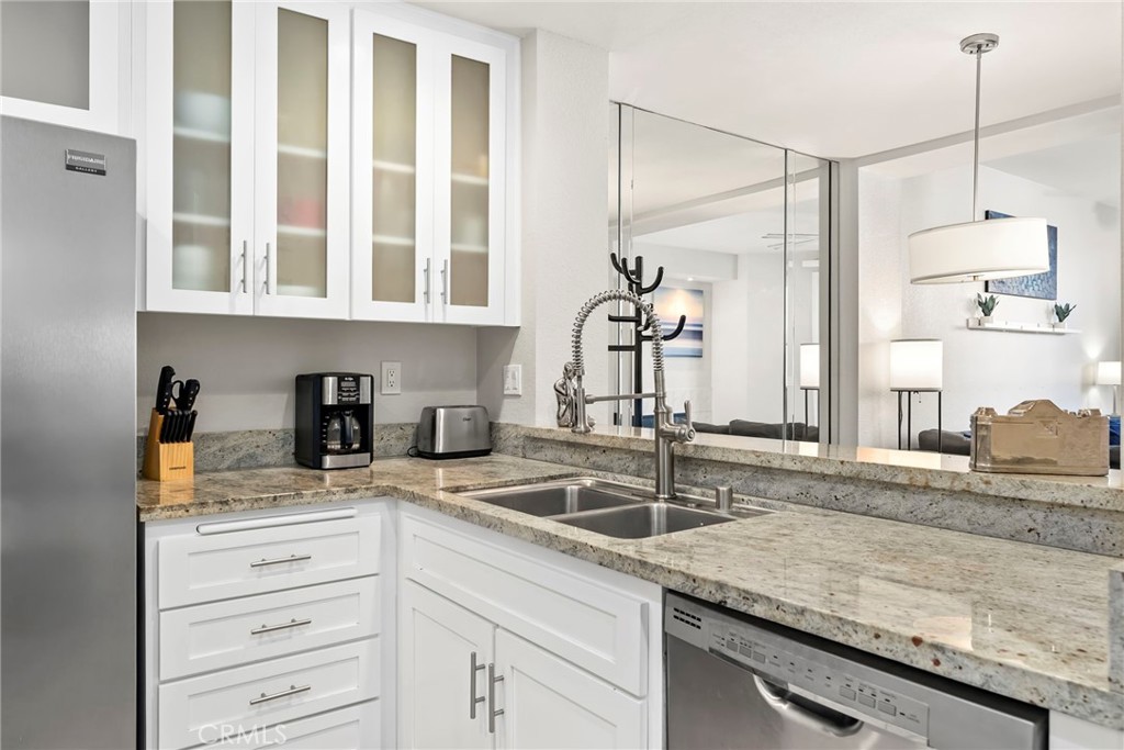 2000 Pacific Coast Highway, Unit 102 Huntington Beach, CA 92648 - Photo 12 of 35 a kitchen with granite countertop a sink and a stove