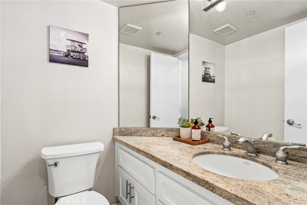 2000 Pacific Coast Highway, Unit 102 Huntington Beach, CA 92648 - Photo 14 of 35 a bathroom with a granite countertop sink mirror and toilet