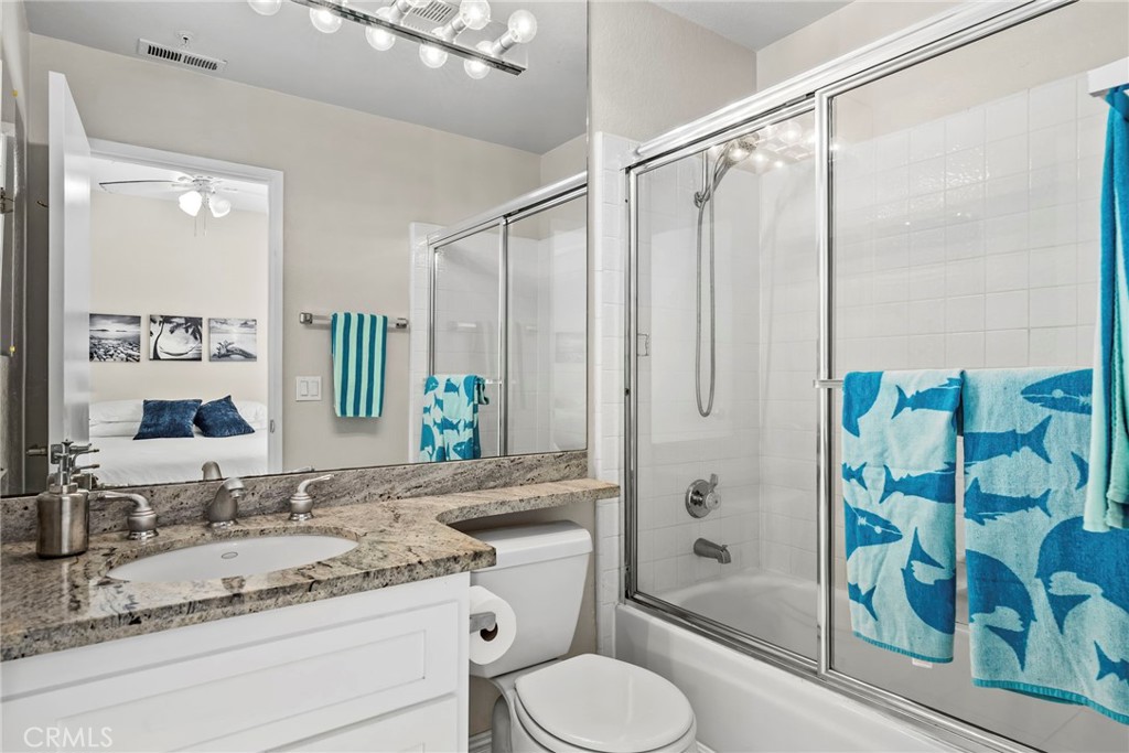 2000 Pacific Coast Highway, Unit 102 Huntington Beach, CA 92648 - Photo 17 of 35 a bathroom with a granite countertop sink toilet a shower and a mirror