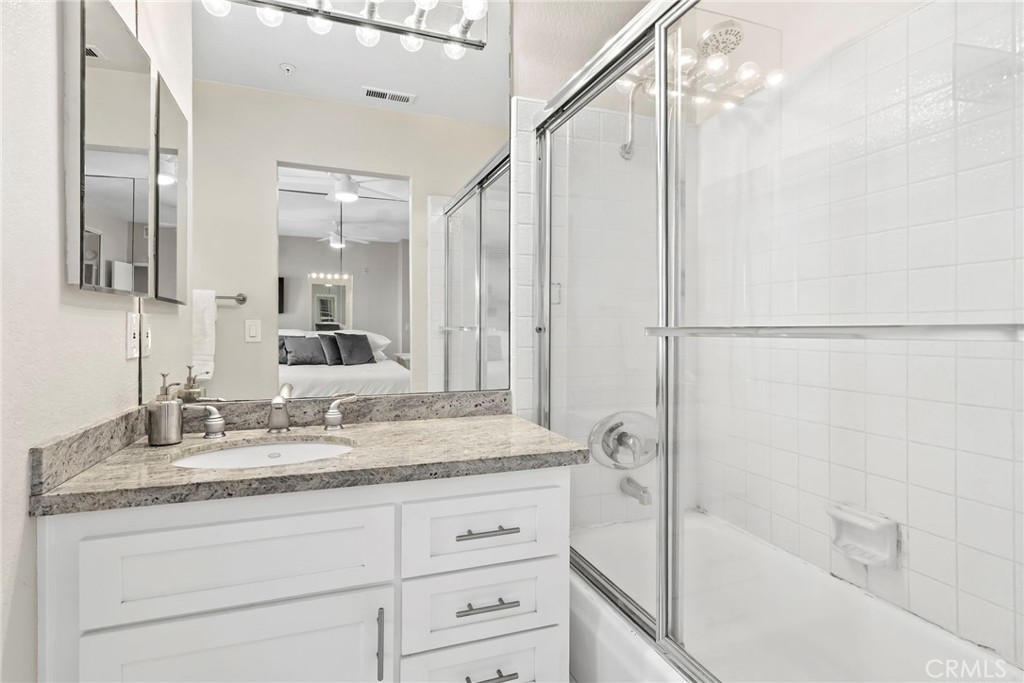 2000 Pacific Coast Highway, Unit 102 Huntington Beach, CA 92648 - Photo 21 of 35 a bathroom with a granite countertop sink a mirror and a bathtub