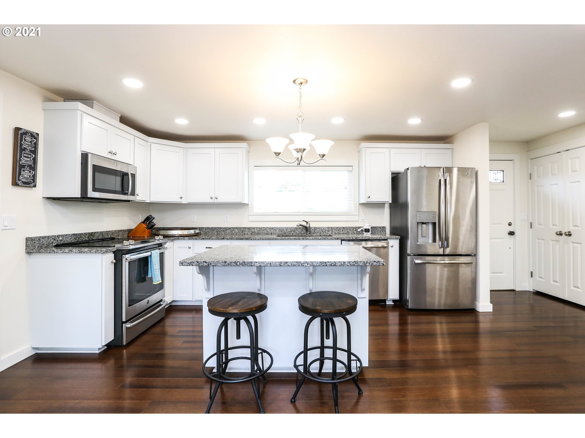 710 53rd Street Springfield, OR 97478 - Photo 6 of 16 a kitchen with stainless steel appliances granite countertop a refrigerator a stove a sink dishwasher a dining table and chairs with wooden floor