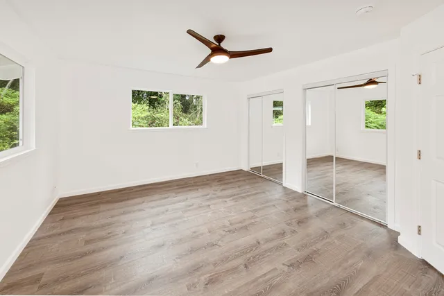 an empty room with ceiling fan and window