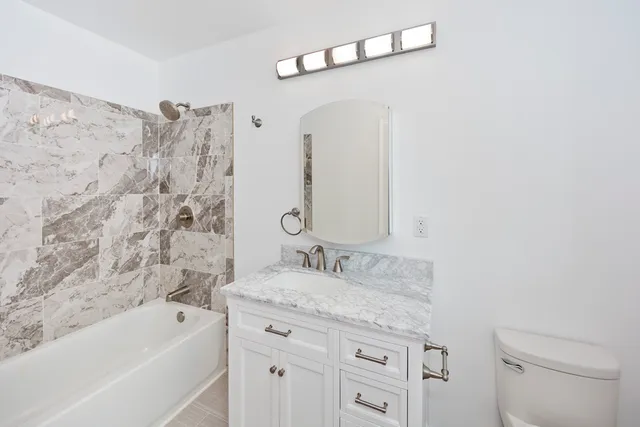 a bathroom with a granite countertop sink a toilet and bathtub