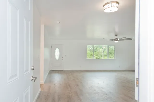 an empty room with wooden floor and windows