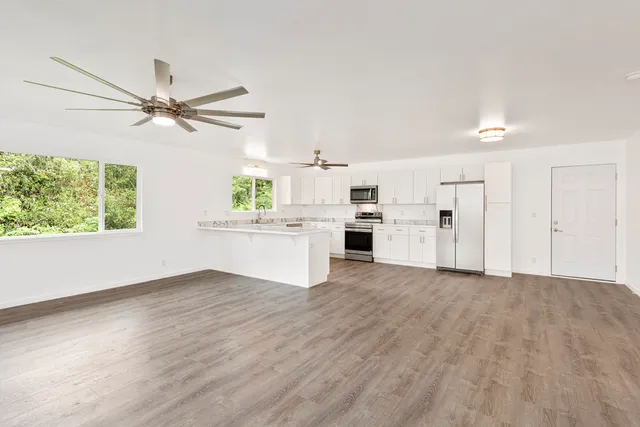 a view of a kitchen with a sink a kitchen island wooden floor and a window