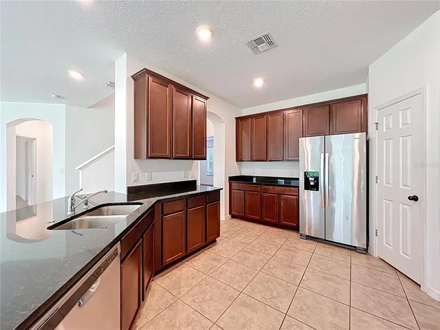 a kitchen with granite countertop a refrigerator and a sink