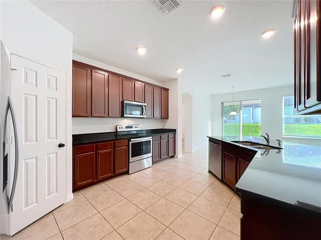 a large kitchen with stainless steel appliances granite countertop a stove a sink and a refrigerator