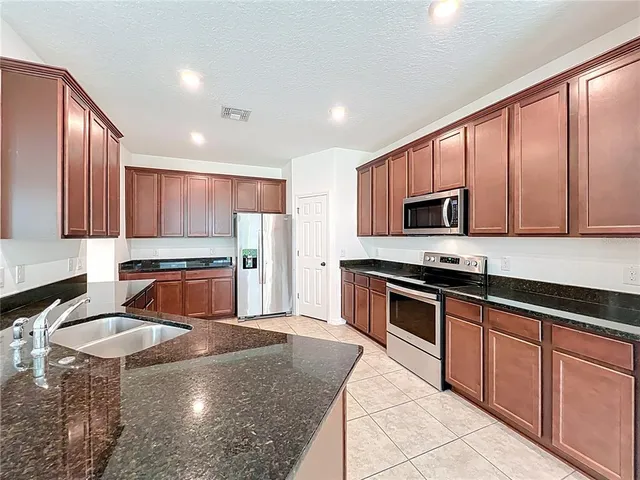 a kitchen with stainless steel appliances granite countertop a stove top oven a sink dishwasher a dining table and chairs with wooden floor