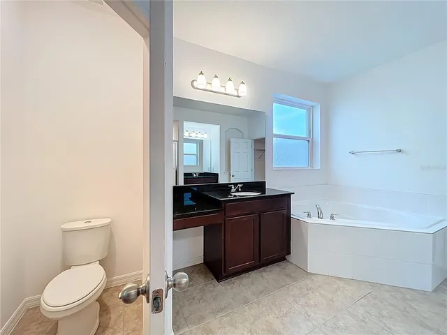 a spacious bathroom with a bathtub a toilet a sink and mirror