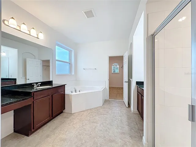 a large bathroom with a tub sink and mirror