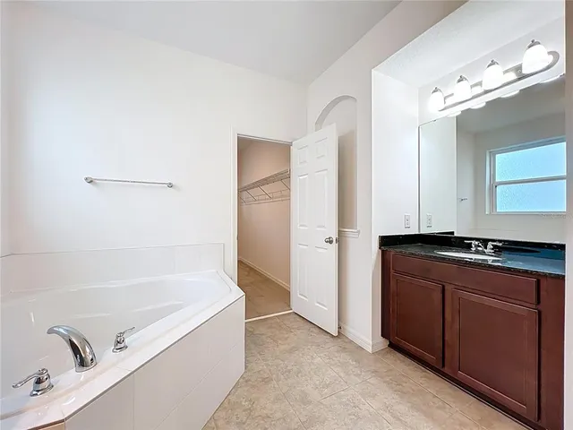 a bathroom with a tub sink and mirror