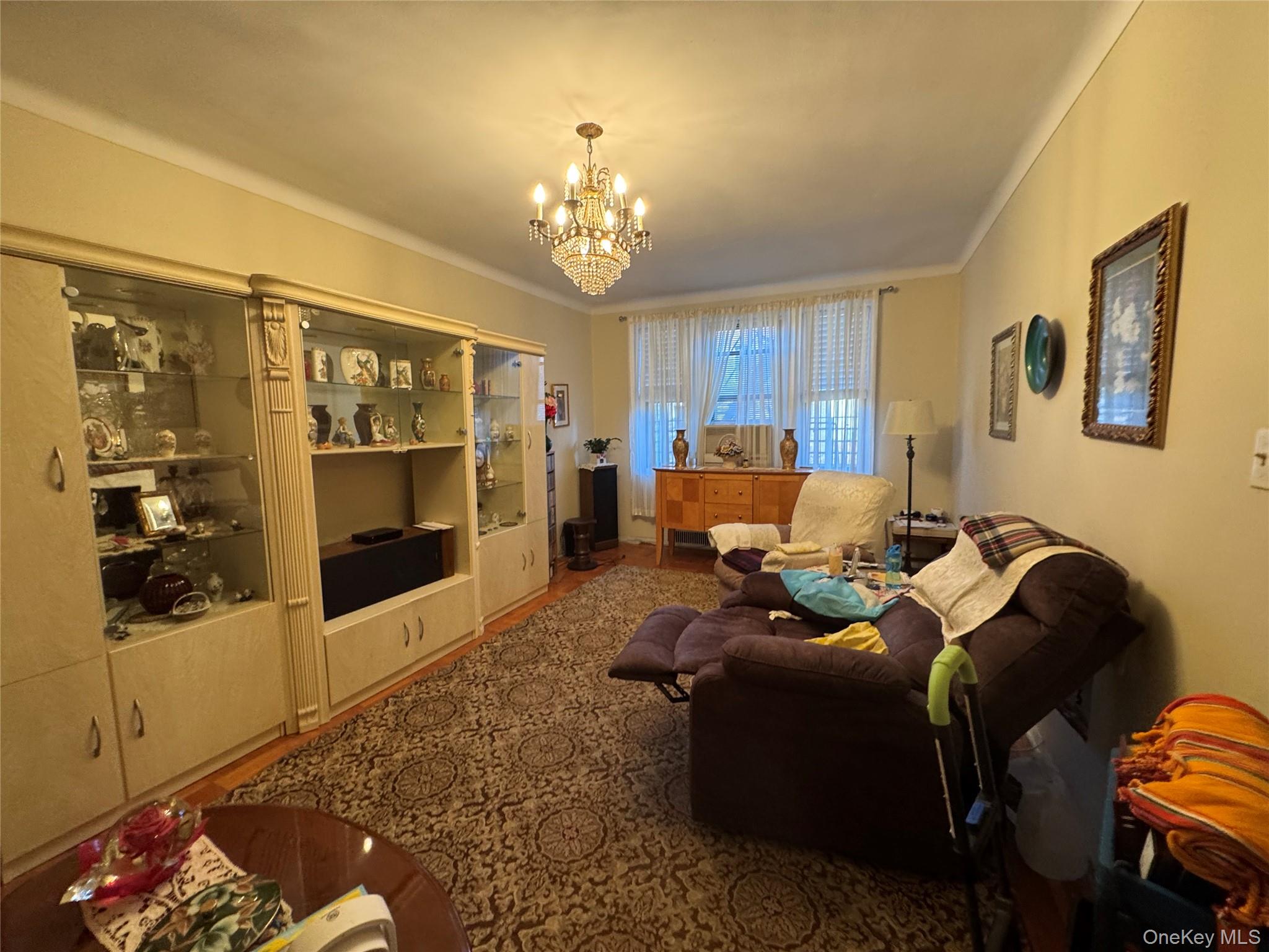 43-30 44th Street, Unit 3F Queens, NY 11104 - Photo 9 of 11 a living room with furniture and a chandelier