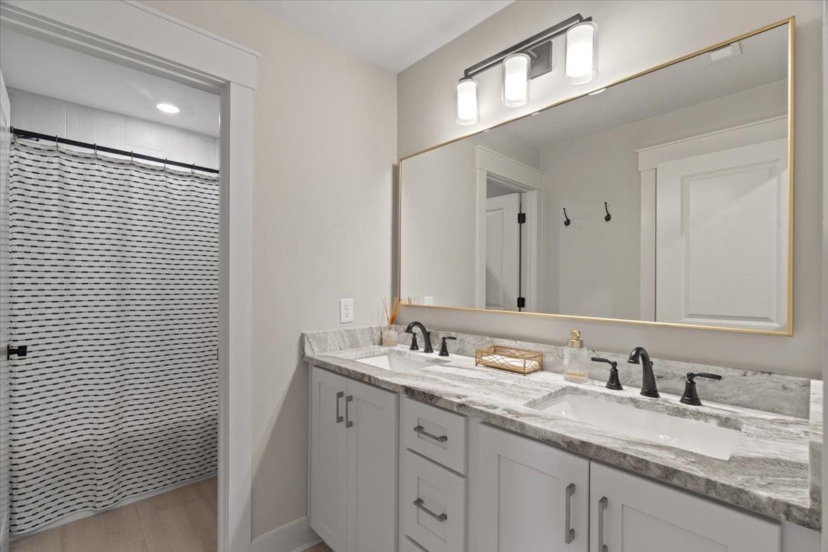 240 Burrows Road Collierville, TN 38017 - Photo 36 of 37 Double vanity featuring undermount sinks, stone countertop, and matte black fixtures