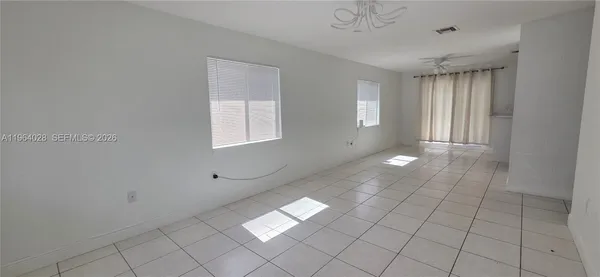a view of an empty room with window and chandelier fan