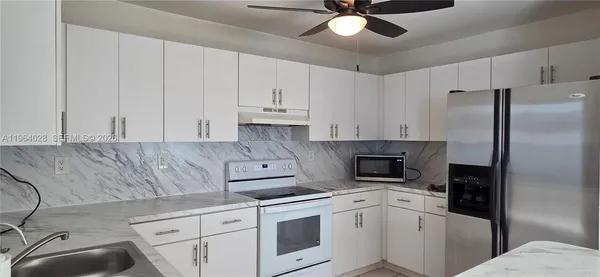 a kitchen with stainless steel appliances granite countertop a refrigerator sink and white cabinets