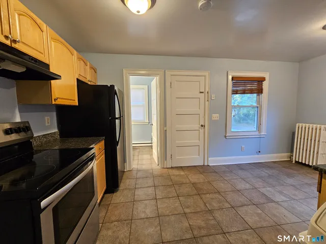 a kitchen with granite countertop a refrigerator and a stove top oven