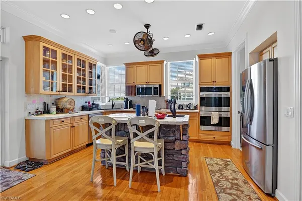 a kitchen with stainless steel appliances granite countertop a stove top oven a refrigerator a dining table and chairs with wooden floor
