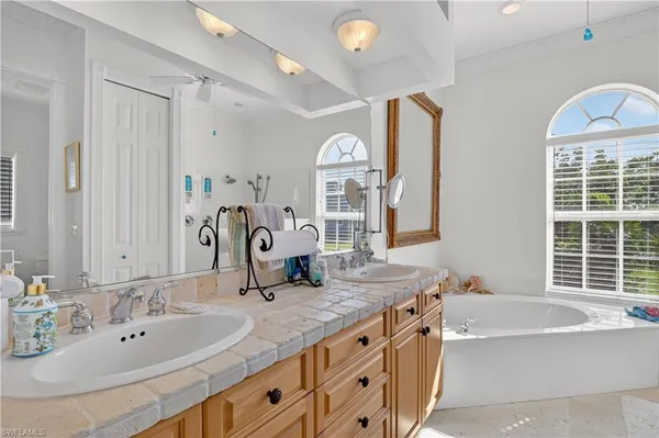 a bathroom with a granite countertop tub double vanity window and a sink
