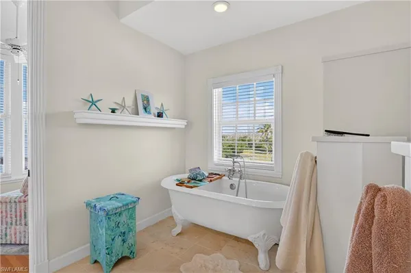 a white bath tub sitting in a bathroom next to a window