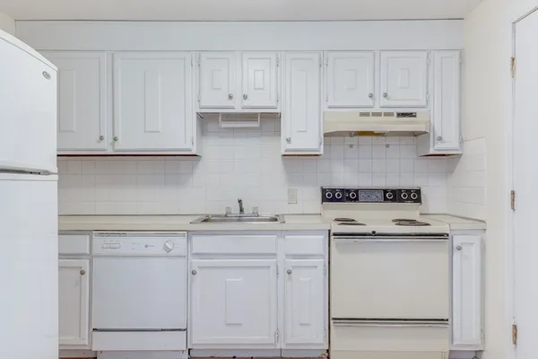 a kitchen with white cabinets and white appliances