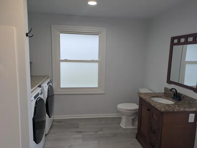 a bathroom with a granite countertop sink toilet and a mirror