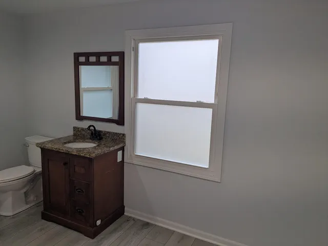 a bathroom with a granite countertop sink and a toilet
