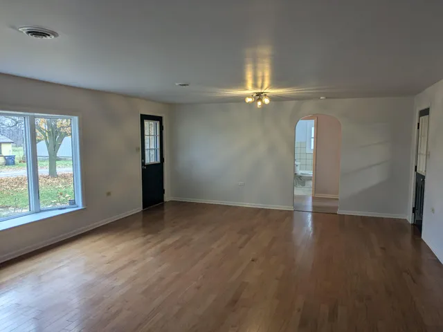 an empty room with wooden floor fan and windows