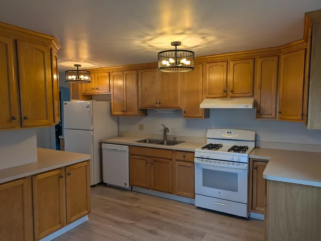 a kitchen with stainless steel appliances granite countertop a sink a stove a refrigerator cabinets and wooden floor