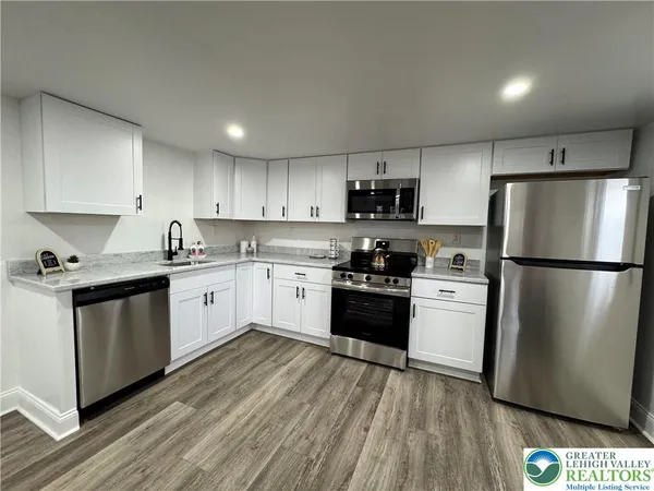 a kitchen with granite countertop a refrigerator stove top oven and sink
