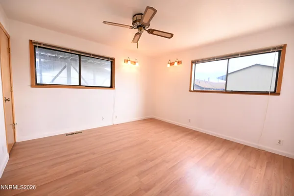 a view of empty room with wooden floor and fan