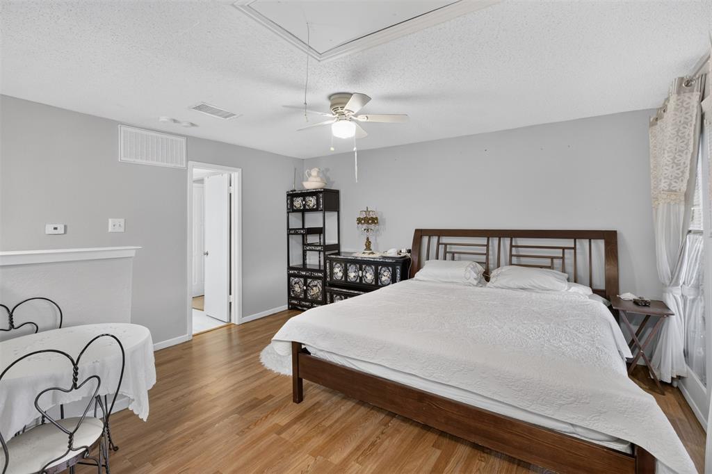 5550 Spring Valley Road, Unit G24 Dallas, TX 75254 - Photo 16 of 23 a bedroom with a bed and dresser with wooden floor