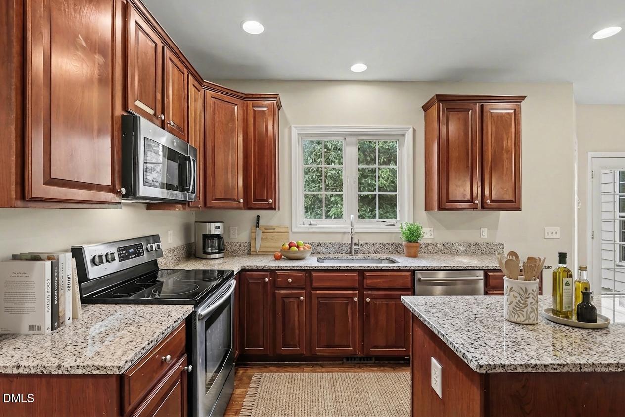 1001 Denfield Court Raleigh, NC 27615 - Photo 17 of 44 a kitchen with stainless steel appliances granite countertop a sink stove and refrigerator
