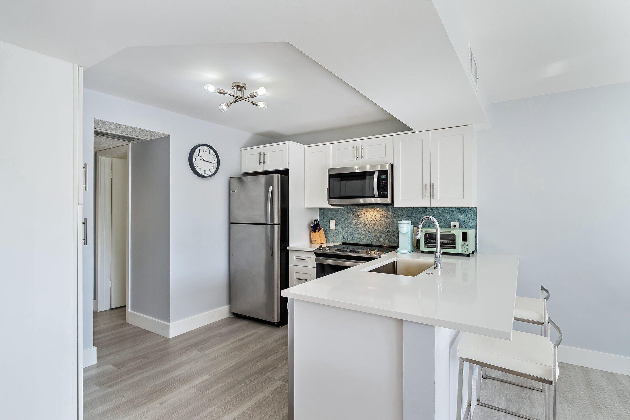 1605 Highway 1, Unit V2204 Jupiter, FL 33477 - Photo 14 of 36 a kitchen with a refrigerator a microwave a sink and cabinets