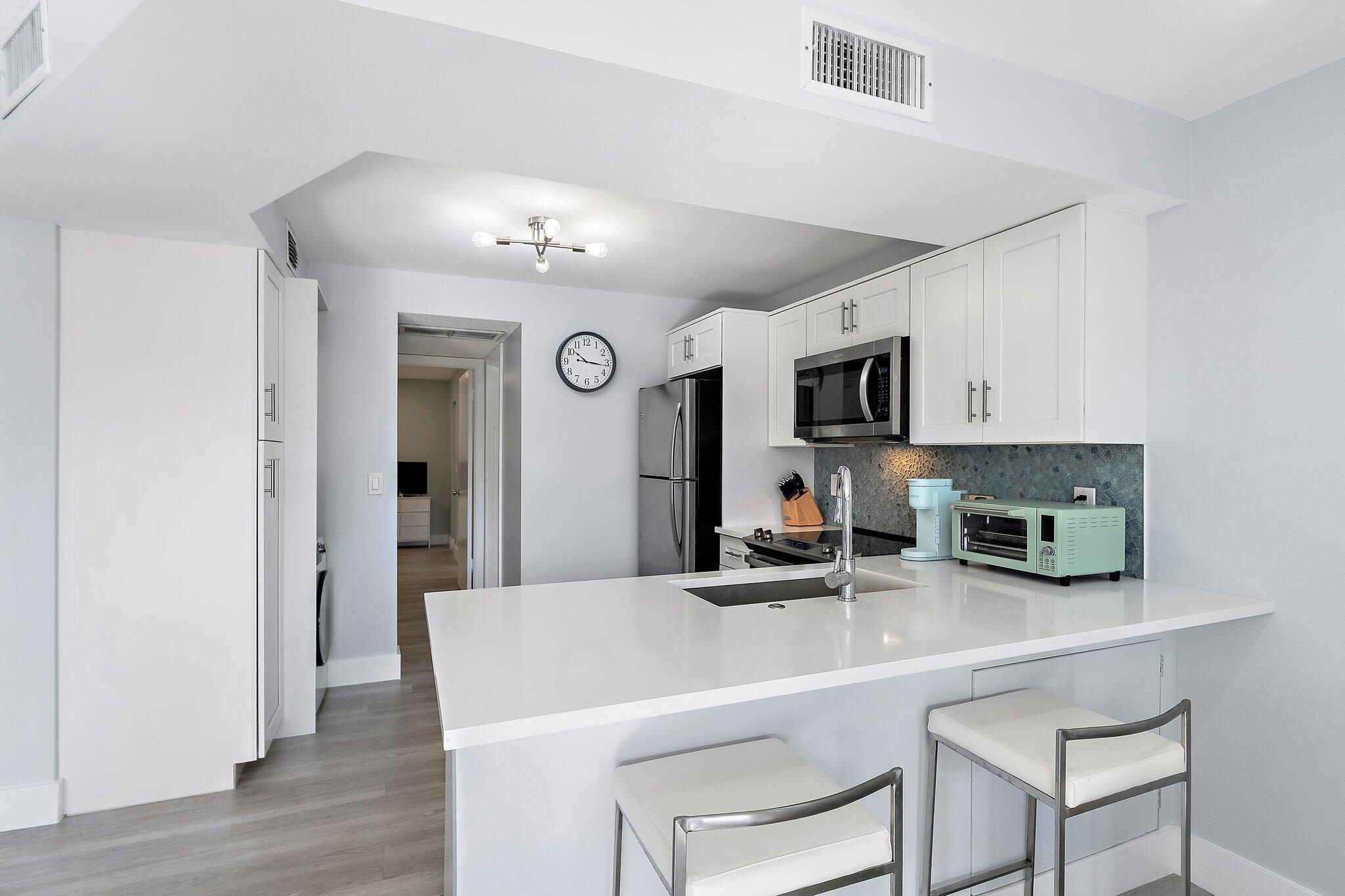 1605 Highway 1, Unit V2204 Jupiter, FL 33477 - Photo 15 of 36 a kitchen with stainless steel appliances a sink a microwave a refrigerator and cabinets