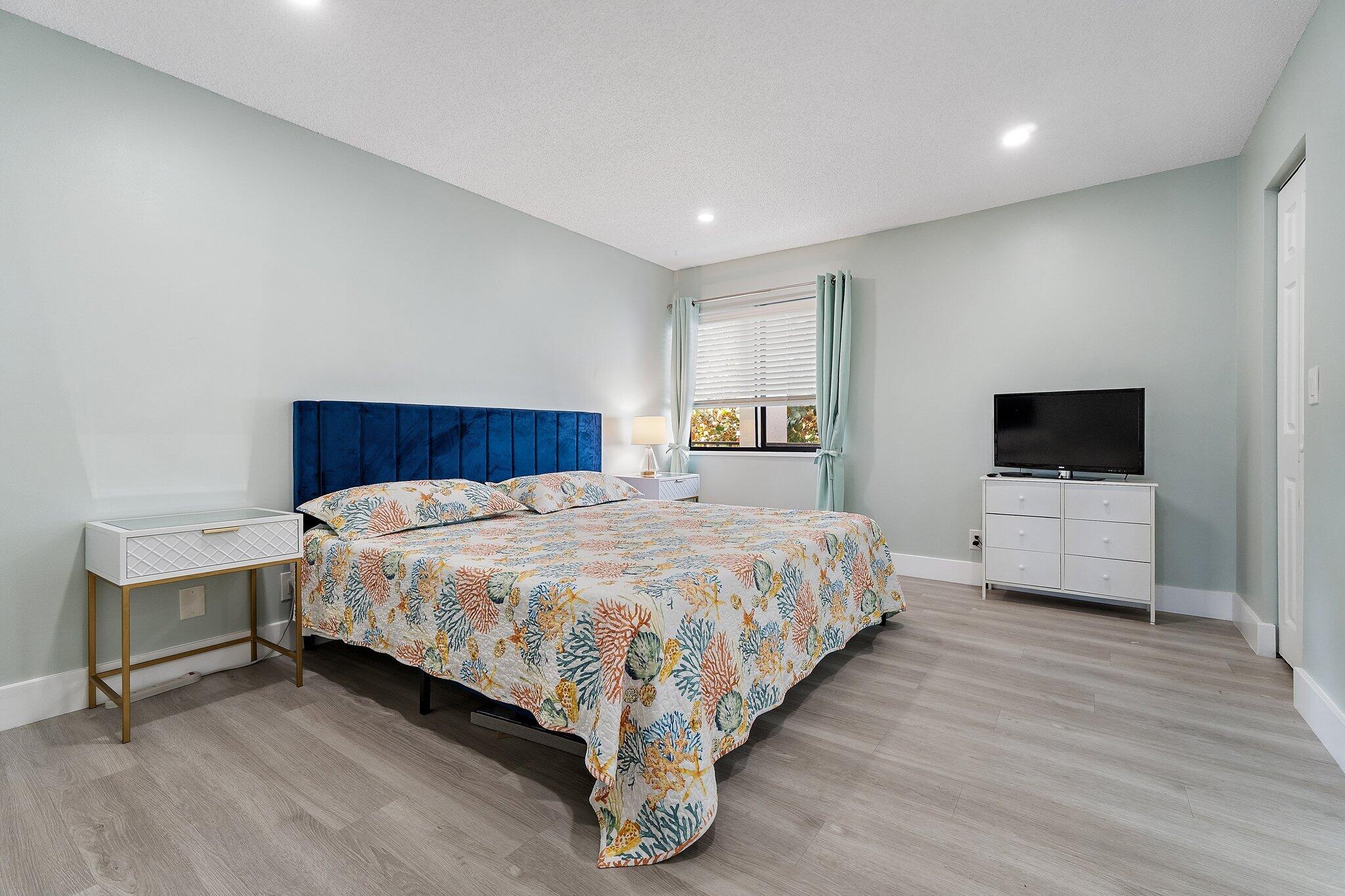 1605 Highway 1, Unit V2204 Jupiter, FL 33477 - Photo 21 of 36 a spacious bedroom with a bed and a flat screen tv