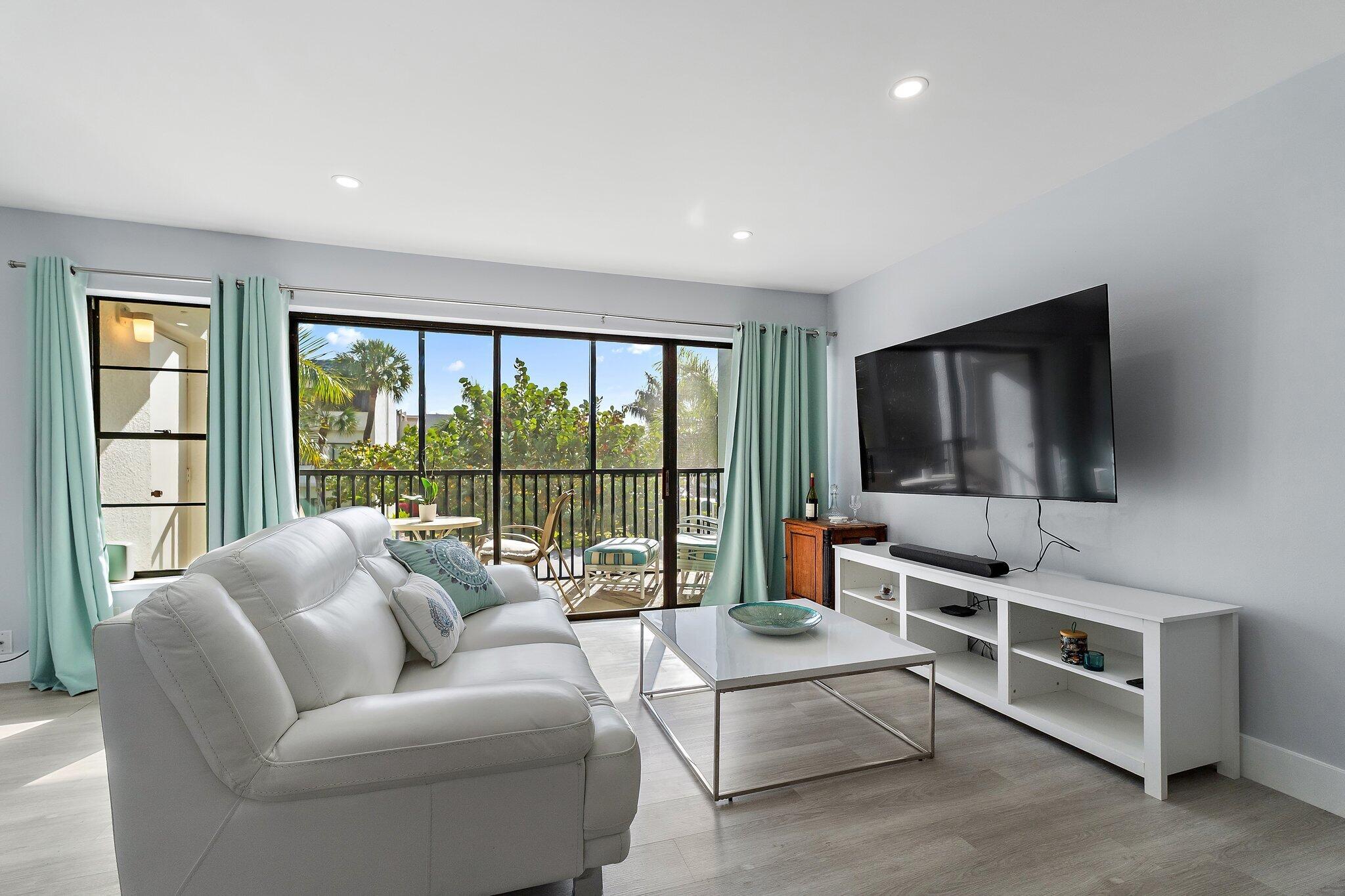 1605 Highway 1, Unit V2204 Jupiter, FL 33477 - Photo 8 of 36 a living room with furniture a flat screen tv and a floor to ceiling window