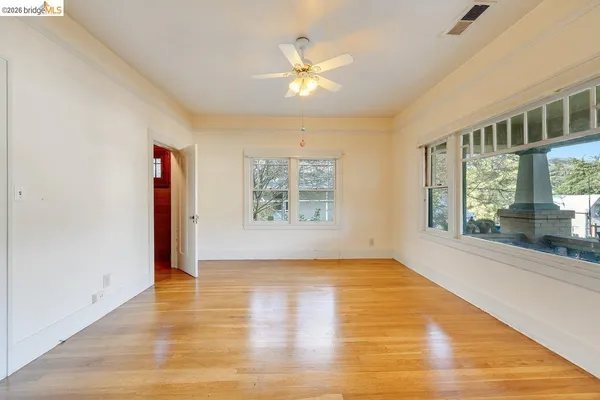 a view of an empty room with a window and wooden floor