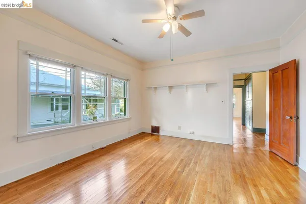 a view of empty room with wooden floor and fan