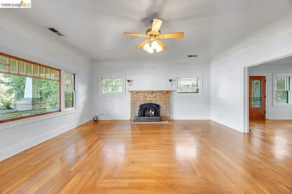 a view of an empty room with window and wooden floor