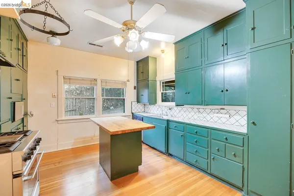 a room with a chandelier a sink dishwasher a dining table and chairs with wooden floor