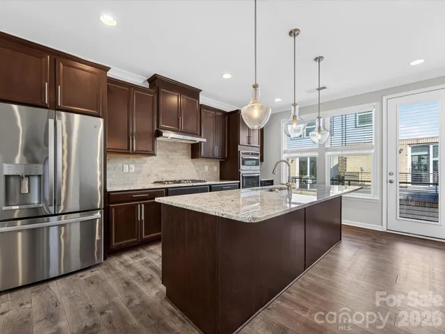 a kitchen with stainless steel appliances granite countertop a sink a stove and a refrigerator