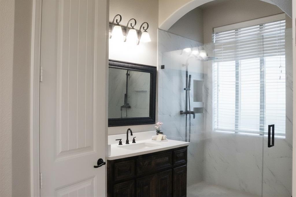 5709 Ridgepass Lane McKinney, TX 75071 - Photo 14 of 19 Bathroom featuring a dark wood-finish vanity with a white countertop, an undermount sink, and a framed mirror